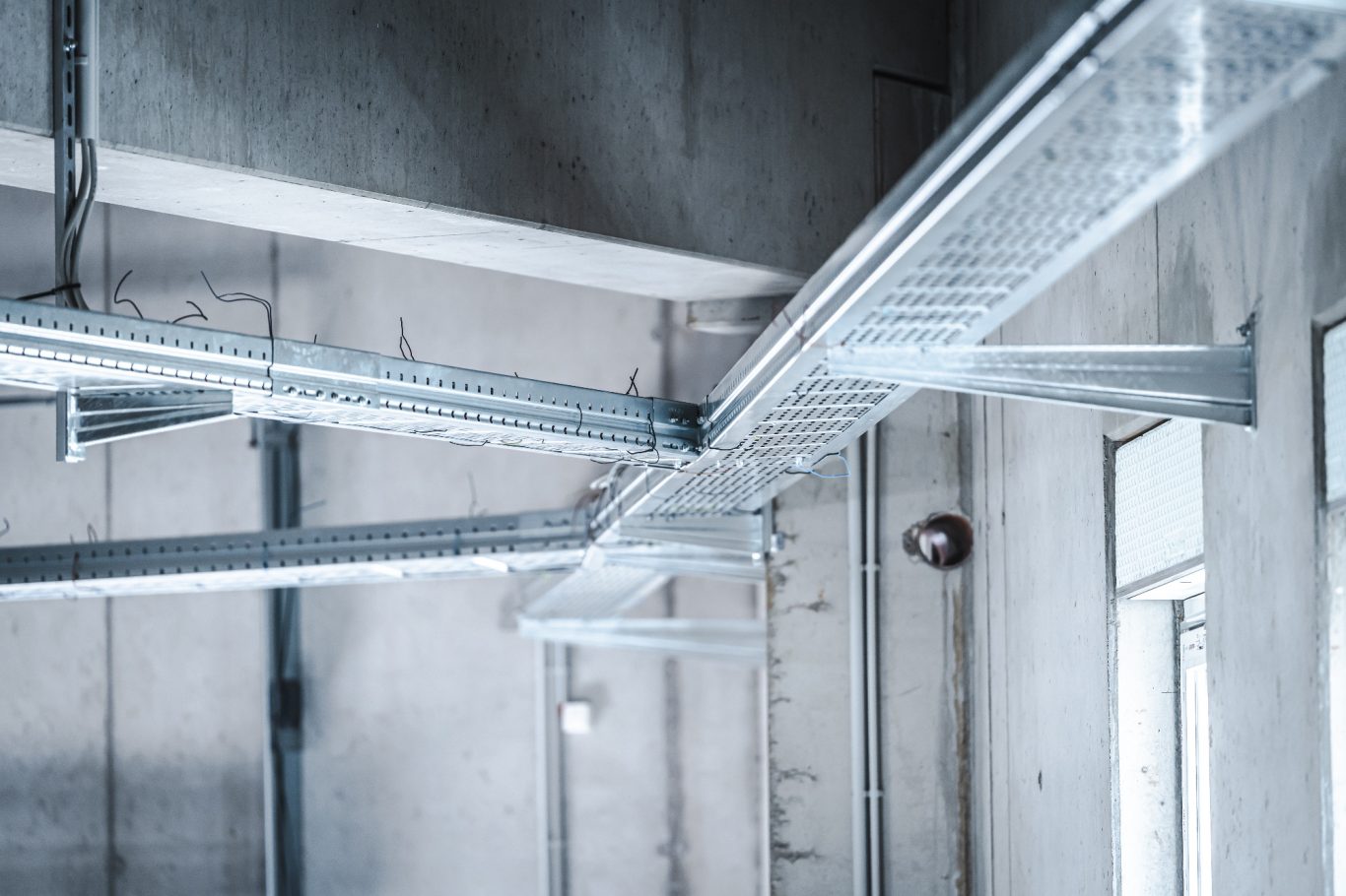 Leitungsführung Metallkonstruktion im Innenraum mit diagonalen Rohrleitungen und Betonwänden.