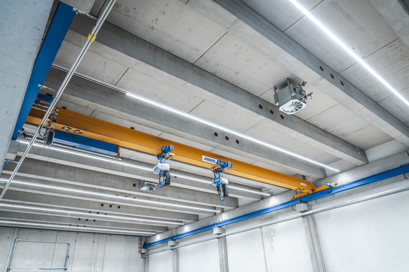 Hallenbeleuchtung Industrielle Decke mit Stahlträgern und einer gelben Kranbahn.
