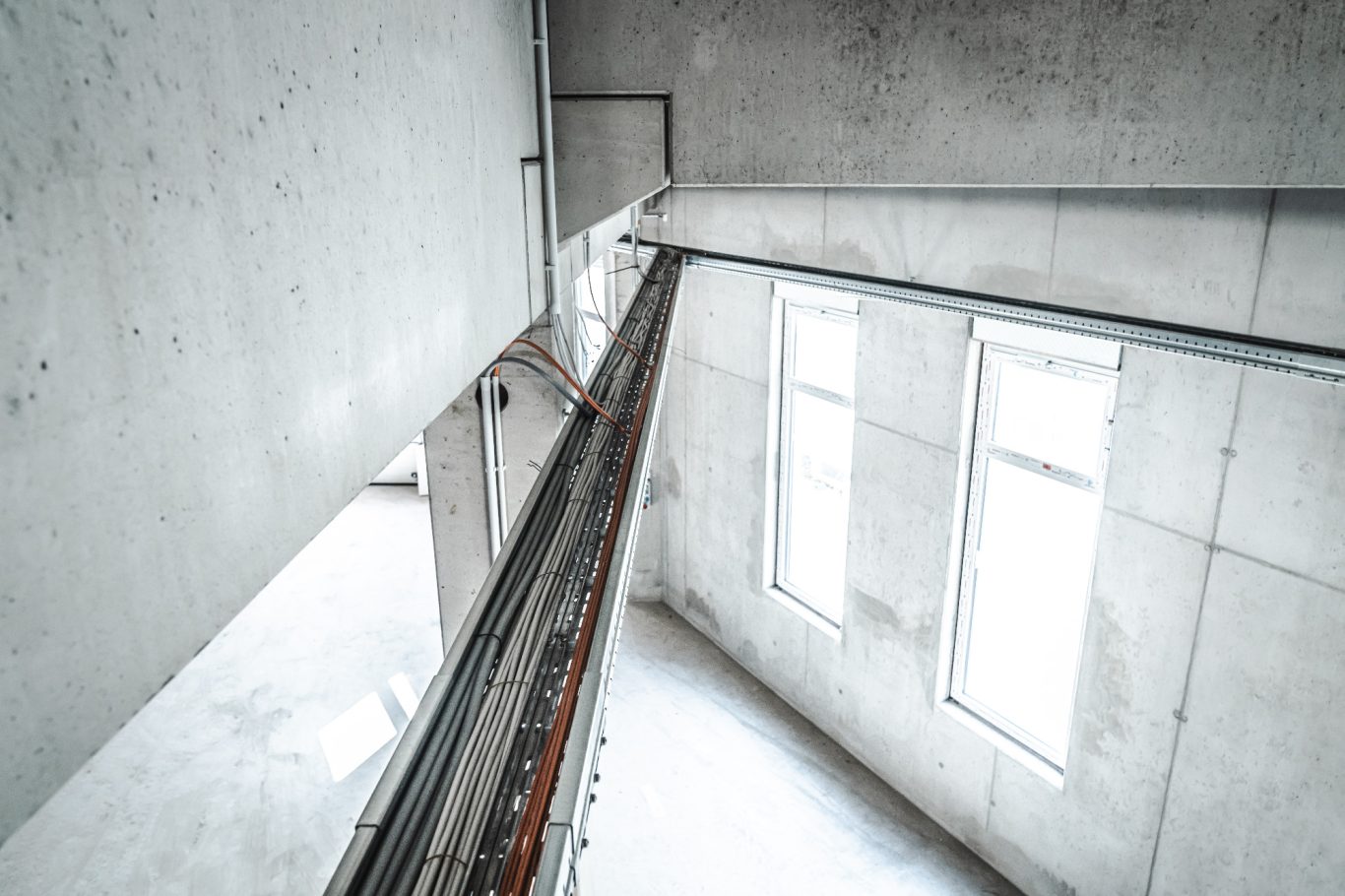 Leitungsführung Klares Betoninterieur mit schmalen Fenstern und vertikalen Linien.