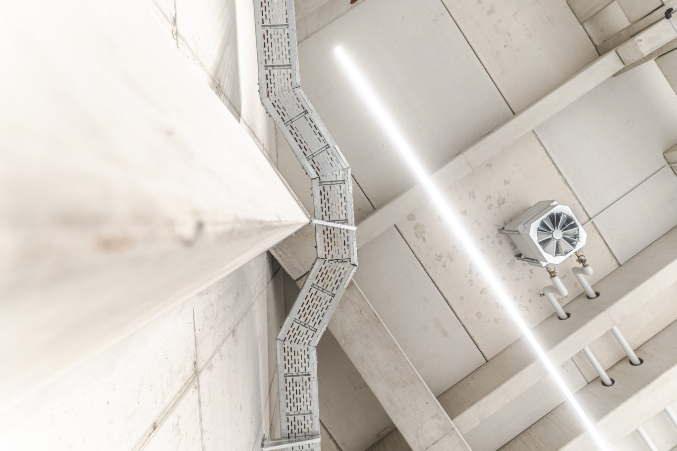 Trassenbau Decke mit Lüftungsschlitzen und modernen Lichtern in einem hellen Raum.