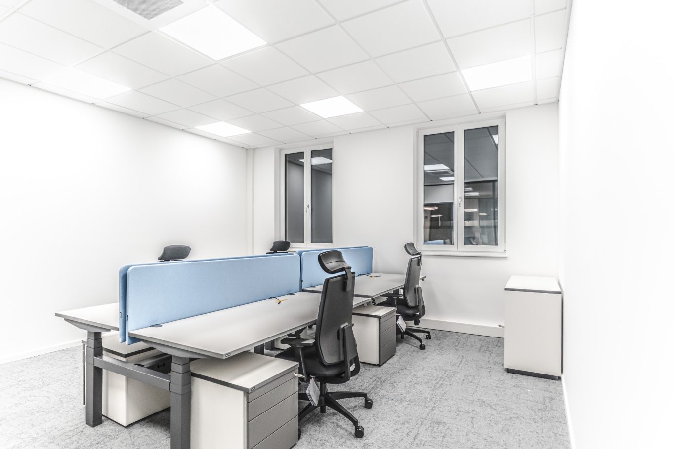 Büro Helle Büroräume mit blauen Trennwänden und Schreibtischen, ausgestattet mit Bürostühlen.