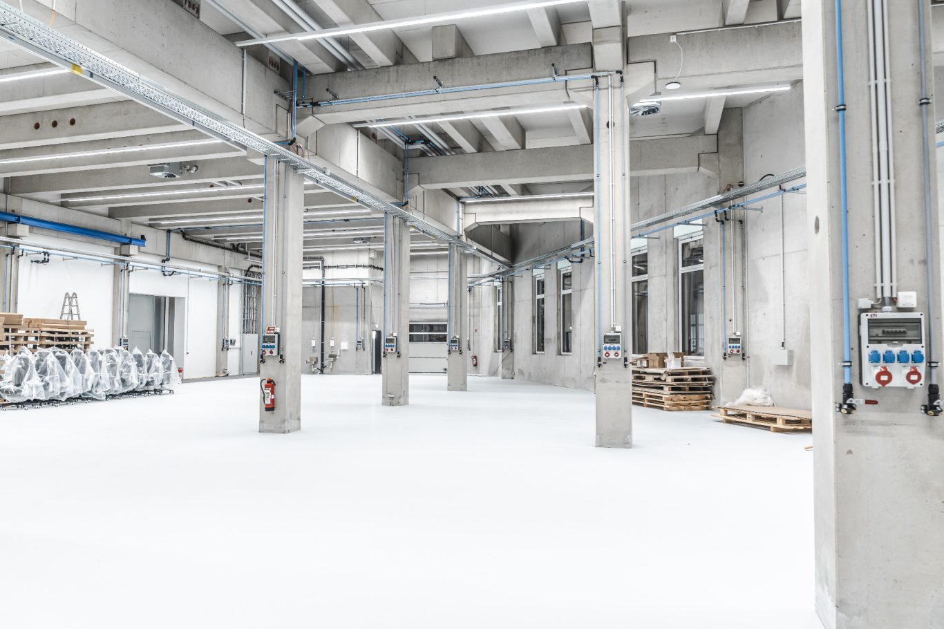 Produktionshalle Heller, geräumiger Lagerraum mit Maschinen und Paletten.