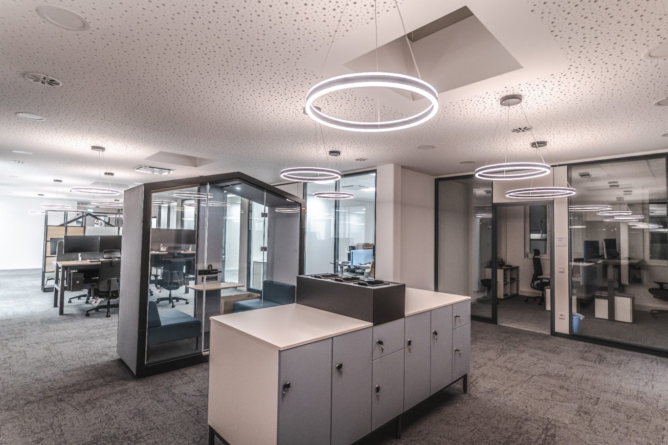 Büroflächen Moderne Büroeinrichtung mit hellen Leuchten und Schreibtischen in einem offenen Raum.