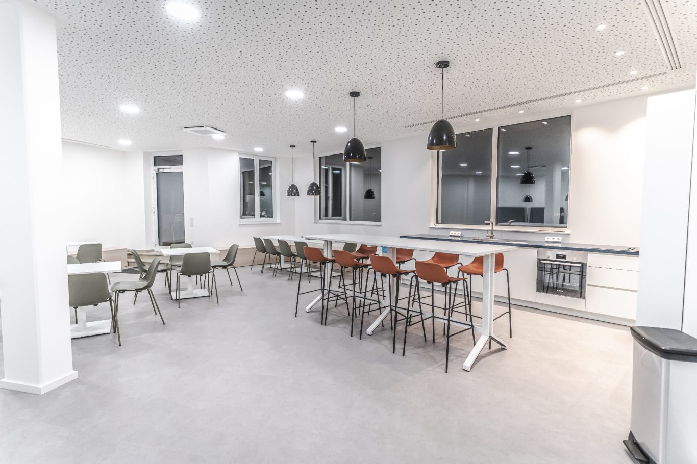 Kantine Geräumiger, moderner Gemeinschaftsraum mit Tischen, Stühlen und einer großen Fensterfront.