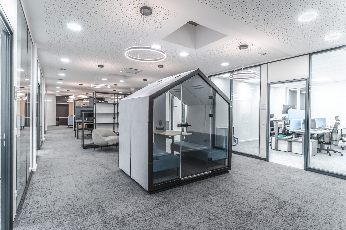 Büroflächen Modern Büro mit einem kleinen Besprechungsraum in Form eines Hauses und hellen Arbeitsplätzen.