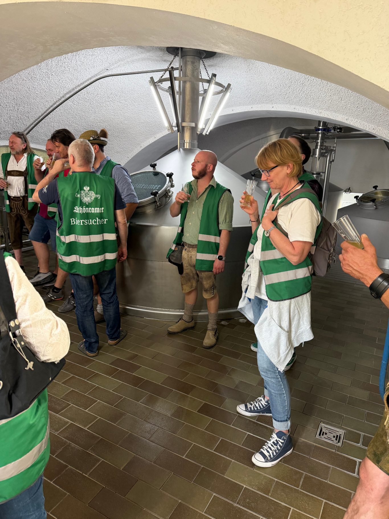 Gruppierung von Personen in grünen Westen, die in einem Innenraum stehen.
