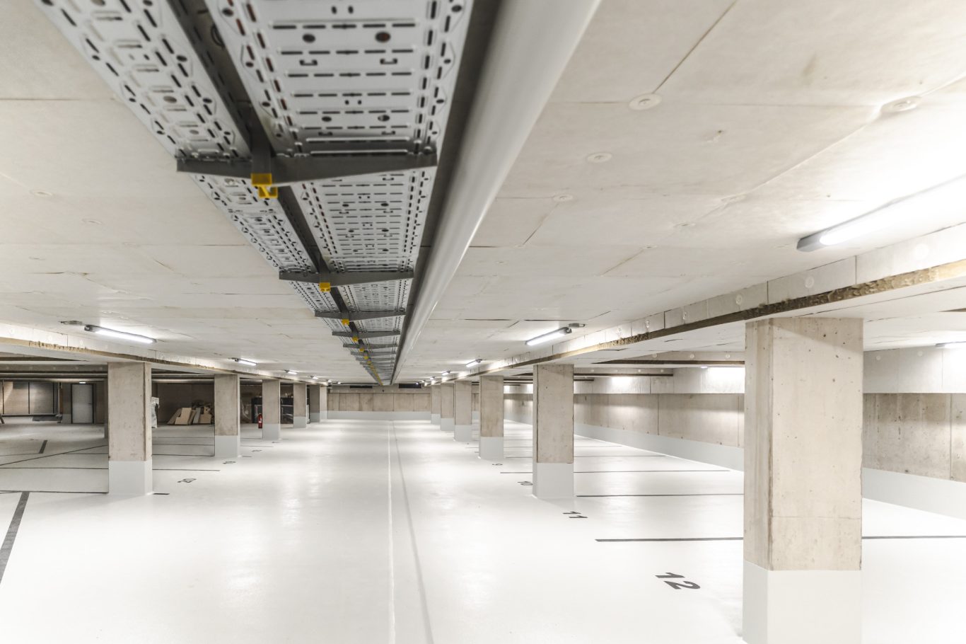 Tiefgarage Helle, moderne Parkgarage mit weißen Wänden und grauen Säulen.
