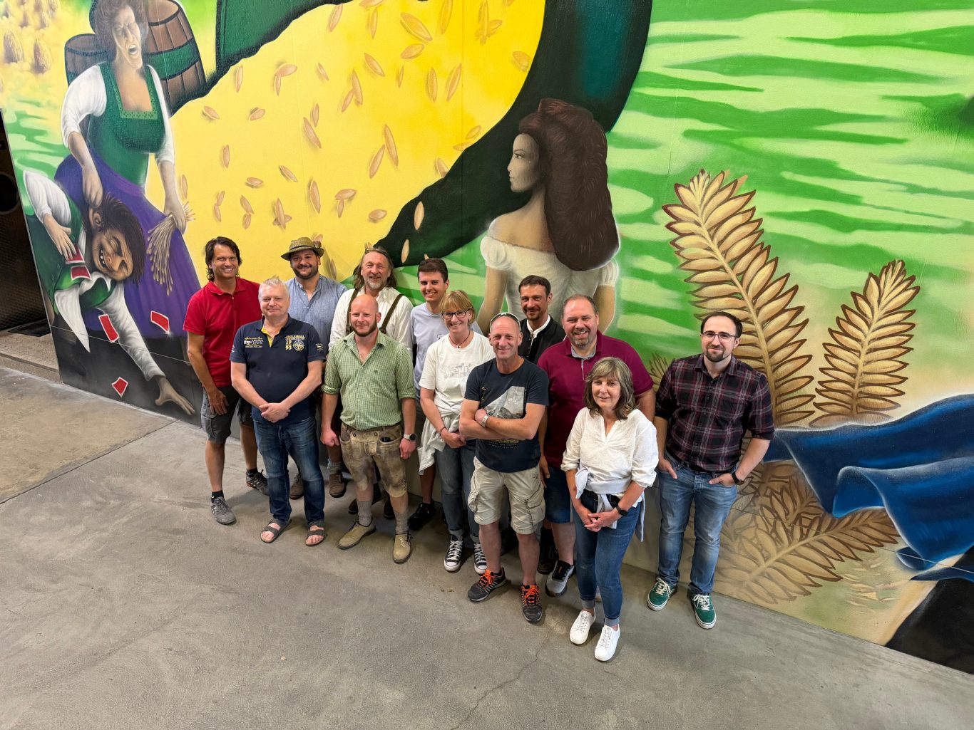 Gruppenfoto von Personen vor einem bunten Wandgemälde.